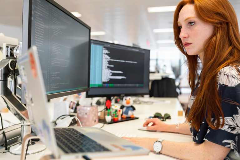 Woman working on computer with code, illustrating learning ReactJS and business tips.