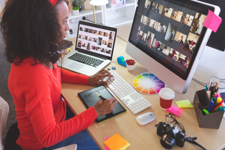 Woman working on computer and tablet designing website graphics and digital design.