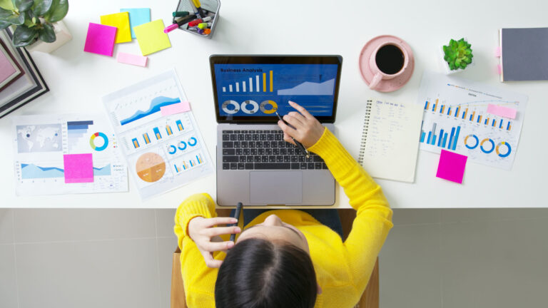SME owner's desk with laptop displaying business charts and graphs, illustrating marketing and business management advice.