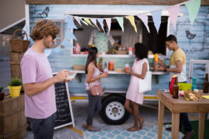 a group of people standing in a room with food and drinks